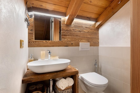 A bathroom with a wooden vanity, a sink, a toilet, and a mirror.. 'Camera Castel Pagan' with Mountain View and Garden