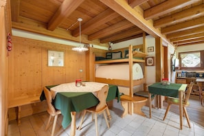Un interior de madera con una mesa de comedor, sillas, una cama litera y una pequeña zona de cocina.