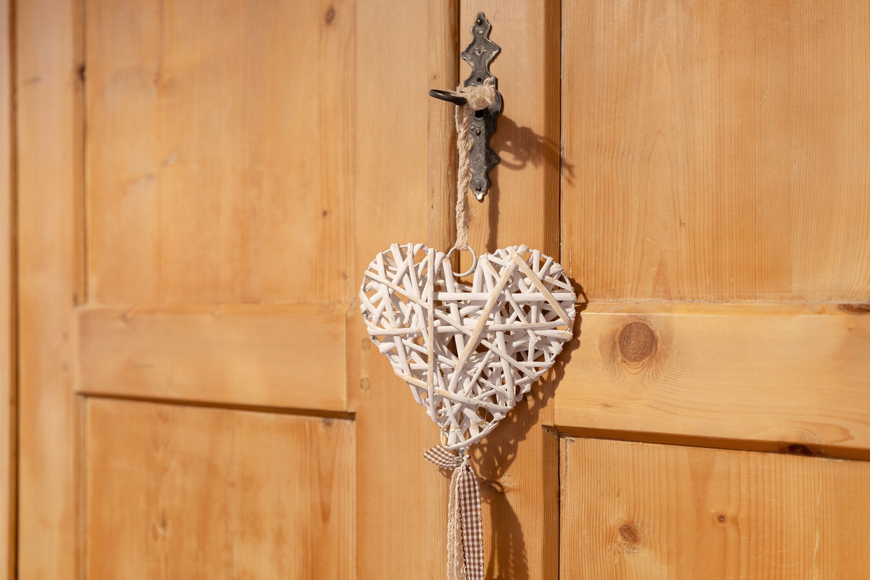 A wooden door with a heart-shaped decoration hanging on it.