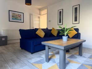 A living room with a blue sofa, a coffee table, and a potted plant.