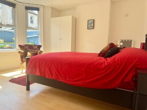 A bedroom with a bed, a window, a wardrobe, and a chair.