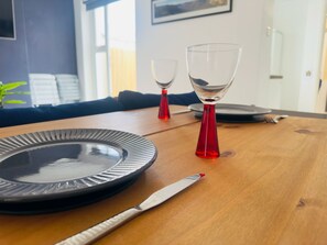 Una mesa de comedor con un plato, un cuchillo y dos vasos rojos.