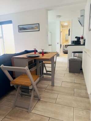 A modern kitchen with a dining area, a sofa, and a small table with two glasses.