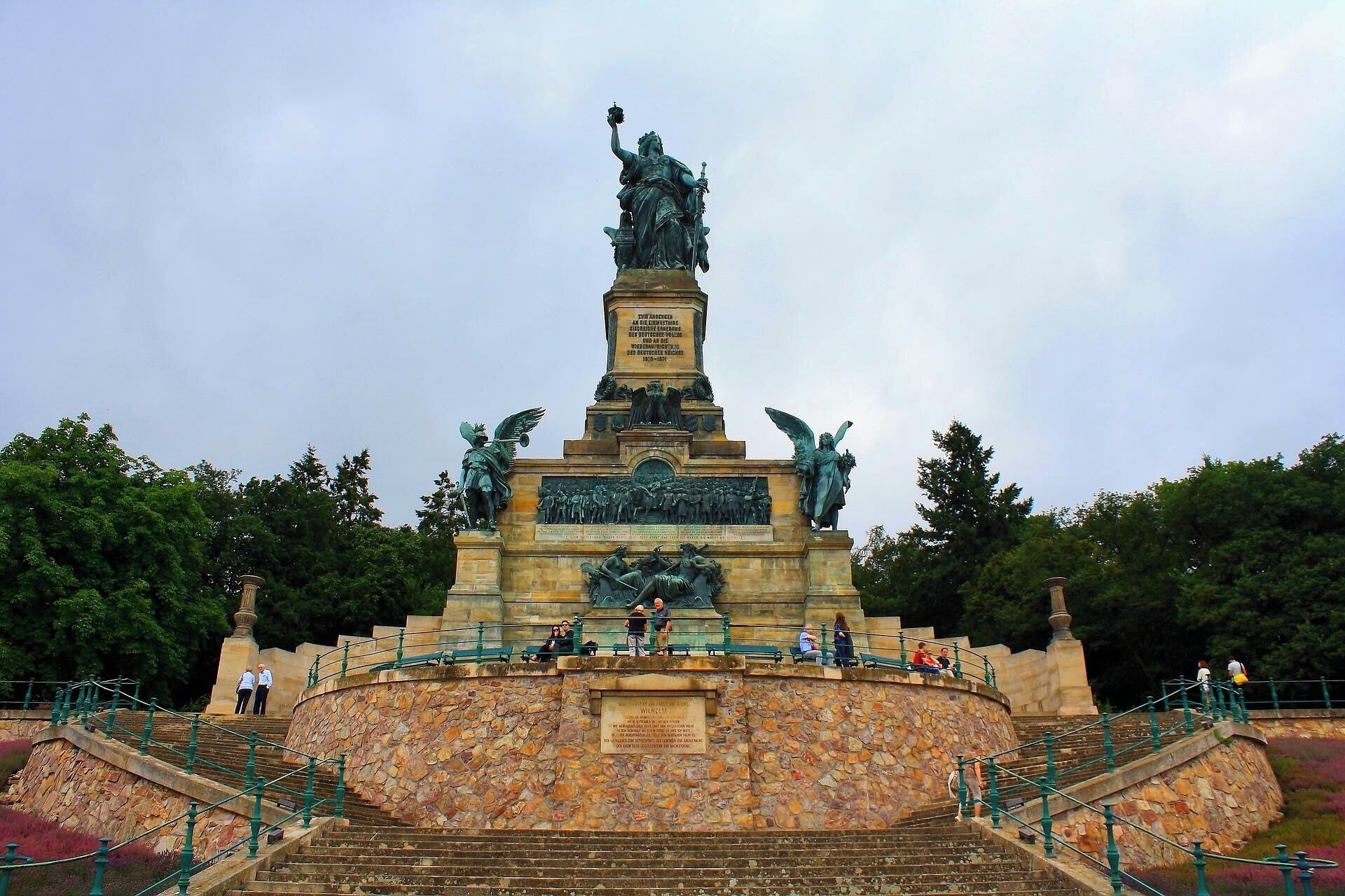 A large monument with a statue on top, surrounded by stone steps and railings.
