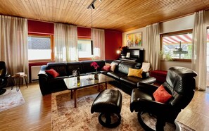 A modern living room with a black leather sofa, a glass coffee table, and a black leather armchair.