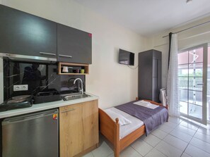 A compact room with a kitchenette, a bed, a TV, and a window with a view.