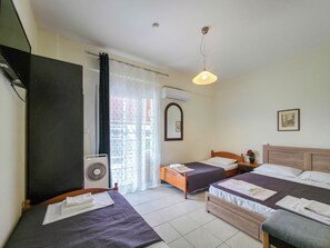 A hotel room with two beds, a window with curtains, a ceiling fan, and a wall-mounted air conditioner.