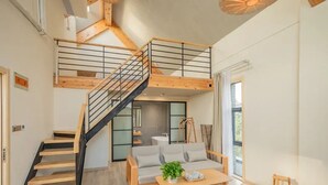 A modern interior with a staircase, a sofa, a coffee table, and a hanging light fixture.