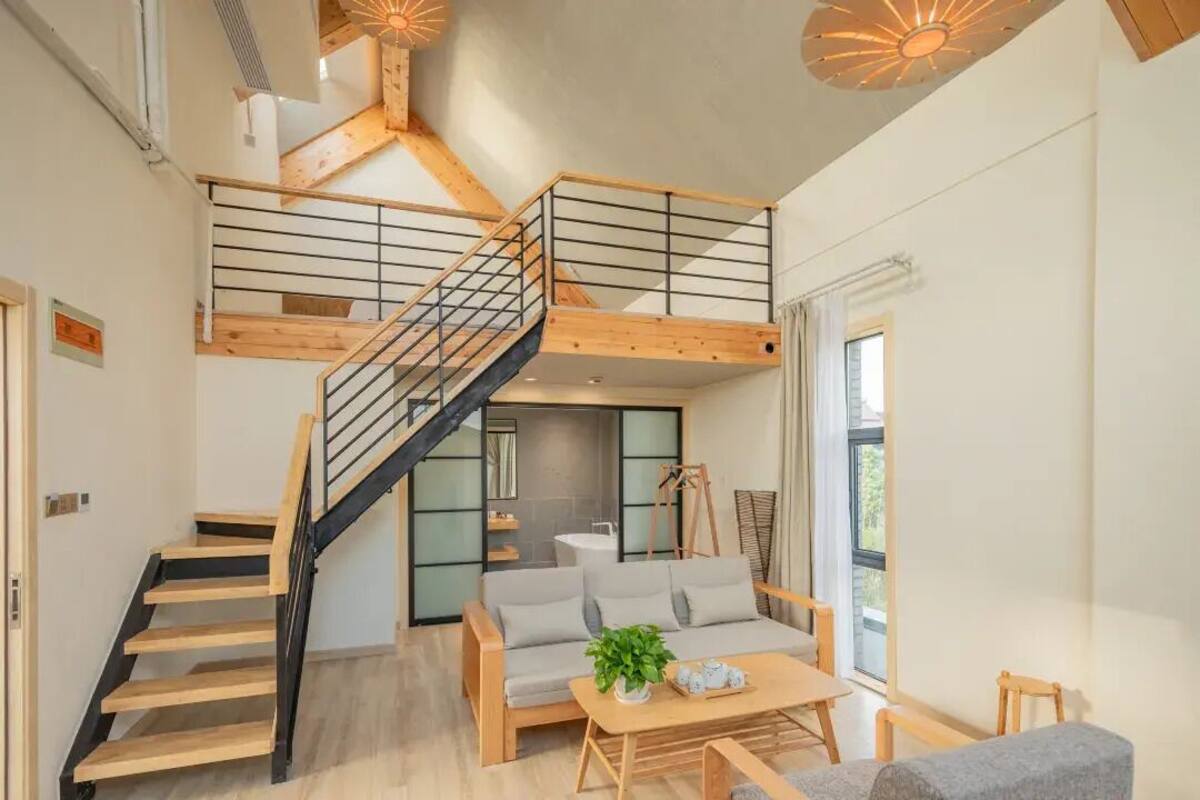 Un interior moderno con una escalera, un sofá, una mesa de centro y una lámpara colgante.