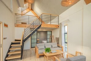 A modern interior with a staircase, a sofa, a coffee table, and a hanging light fixture. - Lake Villa Boutique Guesthouse (Shanghai)