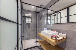 A modern bathroom with a glass-enclosed shower, a wooden vanity with a sink, and a mirror above the vanity.
