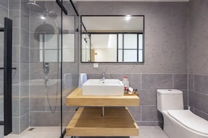 Une salle de bain moderne avec une douche Ă parois de verre, un meuble-lavabo en bois et des toilettes.
