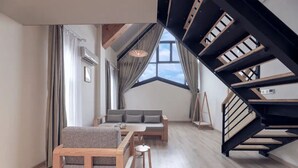 A modern living room with a sofa, a wooden coffee table, and a staircase.