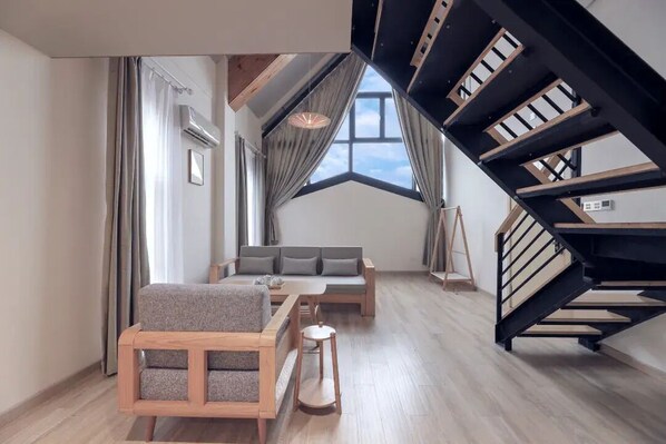 A modern living room with a sofa, a wooden coffee table, and a staircase. - Lake Villa Boutique Guesthouse (Shanghai)