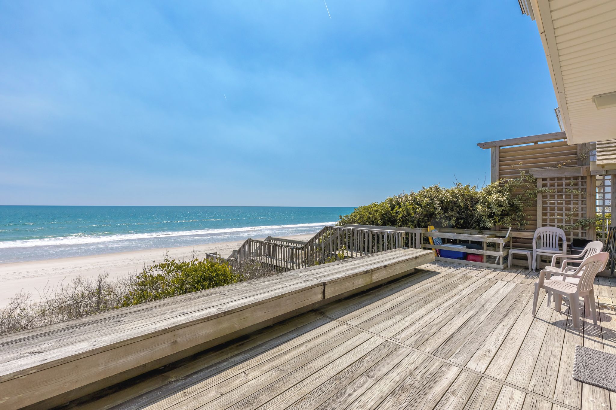 Une terrasse en bois offrant une vue sur la plage et l’océan.