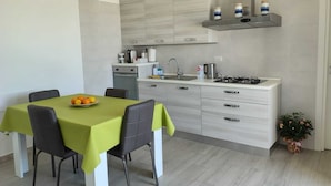 A modern kitchen with a dining table, chairs, a stove, and a sink.