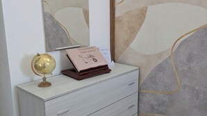 A light grey dresser with drawers, a globe, and a framed certificate on top.