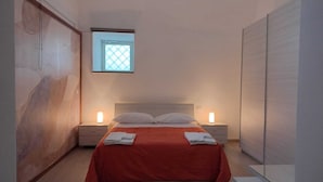 A bedroom with a bed, two bedside tables, a window with a view, and a wardrobe.