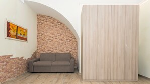Een kamer met een bakstenen muur, een bank en een kledingkast.