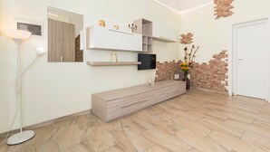 Een modern interieur met een ingebouwde bank, een aan de muur bevestigde televisie en decoratieve objecten.