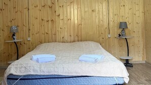 Ein Zimmer mit Holzwänden, einem Bett, zwei Nachttischen und Lampen.