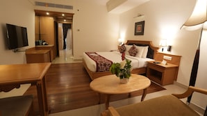 Een hotelkamer met een bed, nachtkastjes, een televisie, een bureau en een stoel.