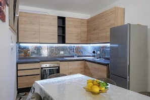 Eine kleine Küche mit Holzausstattung, einem Edelstahlkühlschrank und einem Tisch mit Zitronen.