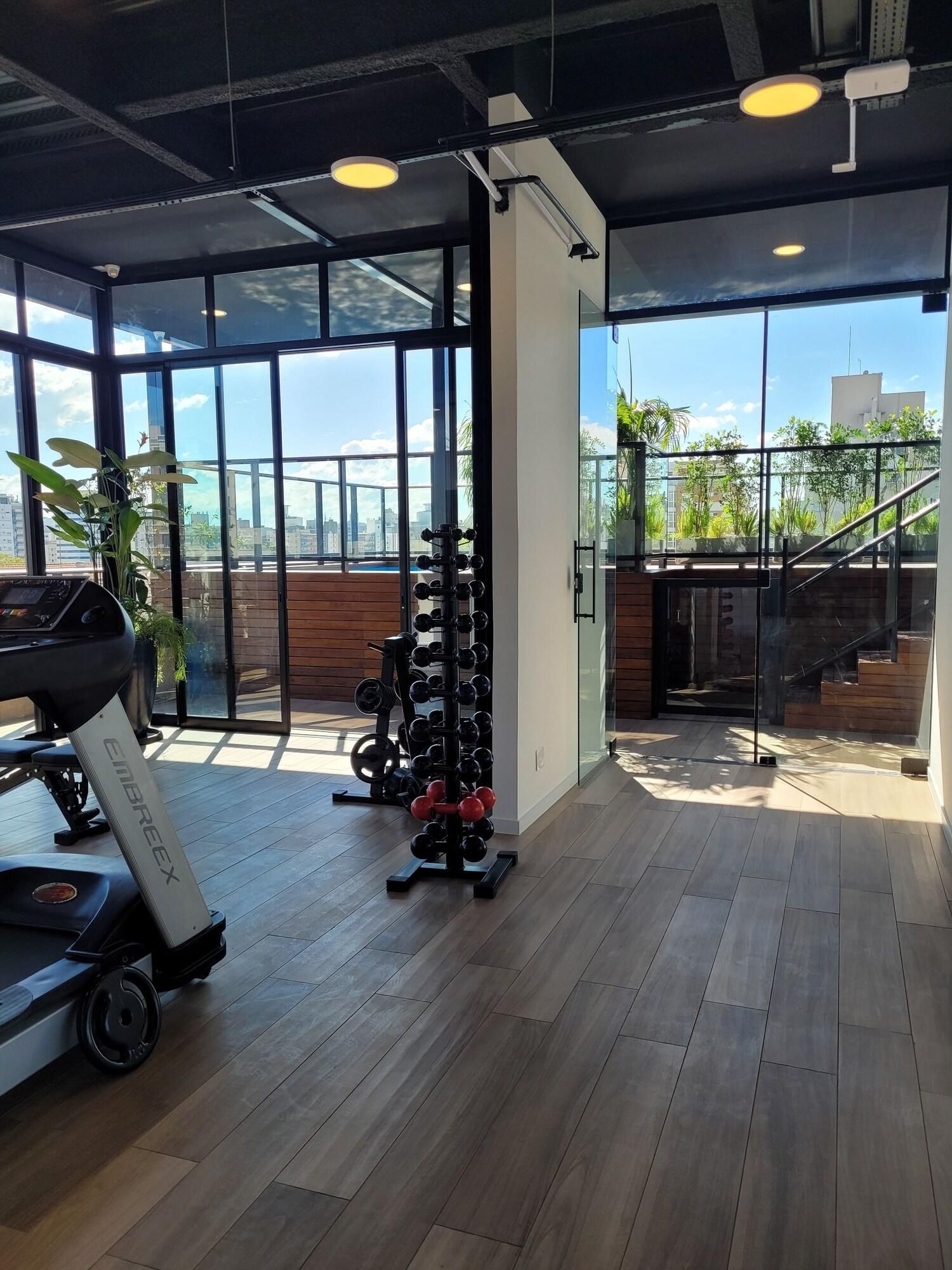 A gym with exercise equipment, large windows, and a view of buildings outside.