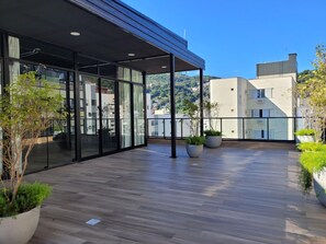A modern building with large glass windows, a wooden deck, and potted plants. - Bewiki (Florianópolis)