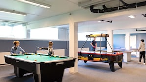 A pool table with balls, a ping pong table, and a person playing ping pong. - Sondervig Holiday Center (Ringkobing)