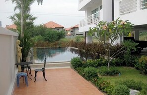 Ein Wohngebiet mit Schwimmbad, Terrasse mit Sitzgelegenheiten und kleinem Garten.