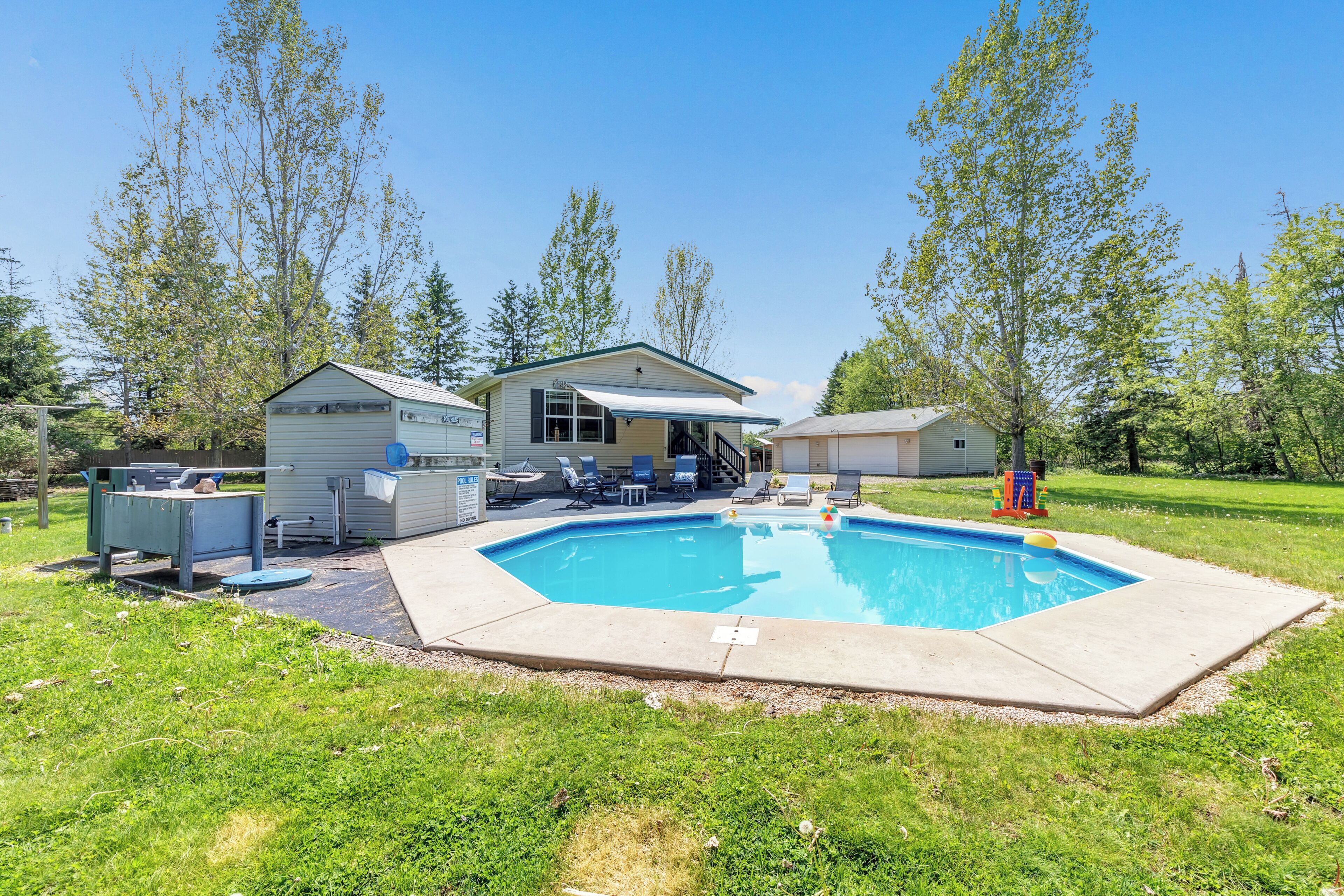 A residential property with a swimming pool, a covered patio, and a small shed.