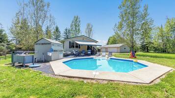 A residential property with a swimming pool, a covered patio, and a small shed.