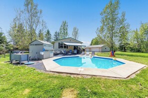 Ein Wohnhaus mit Swimmingpool, überdachter Terrasse und kleiner Gartenhütte.