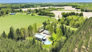 A large property with multiple buildings, expansive green fields, and dense forested areas. - Brand new listing!!! Relax and unwind at this stunning Northwoods pool house featuring a private in-ground pool, fire pit, patio, garage space, and sleeping for 11 guests! (Mountain)