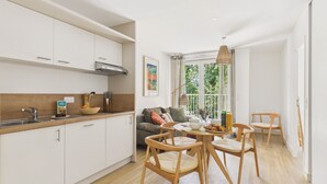 Una cocina moderna con armarios blancos, encimera de madera y un comedor con sillas y mesa de madera.