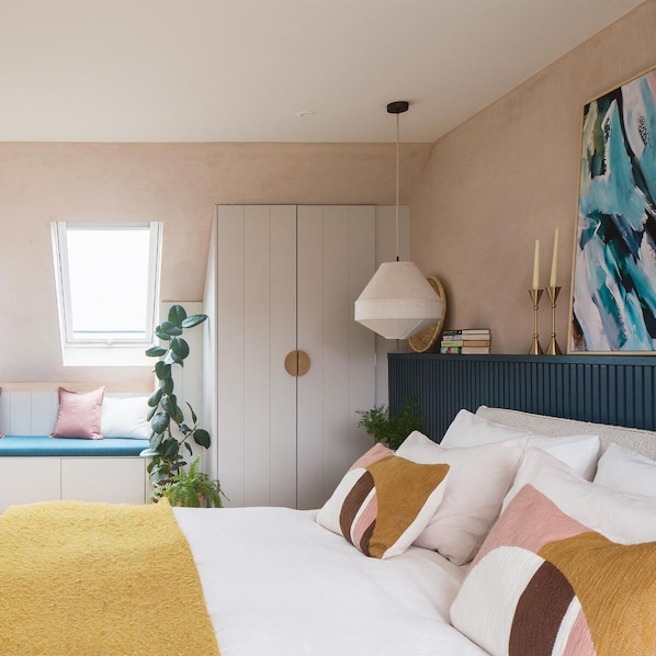 Ein Schlafzimmer mit einem Bett, einem Fenster, einer Pflanze und einem GemÀlde an der Wand.