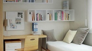 Ein Schlafzimmer mit einem Bett, einem Schreibtisch und Regalen mit BĂŒchern.