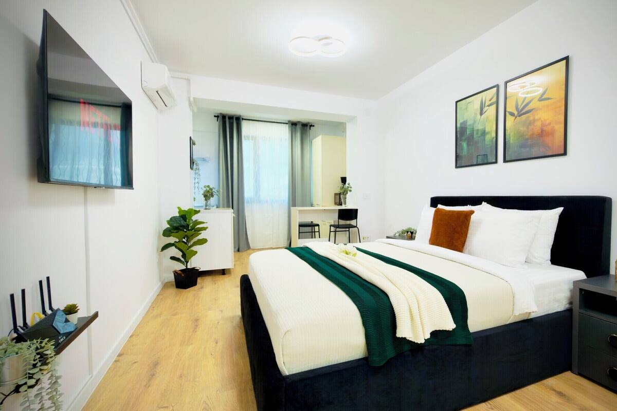 A modern bedroom with a bed, bedside table, and a desk area.