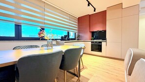 Une cuisine moderne avec un coin repas, comprenant une table en bois, des chaises grises et un vase avec des fleurs.