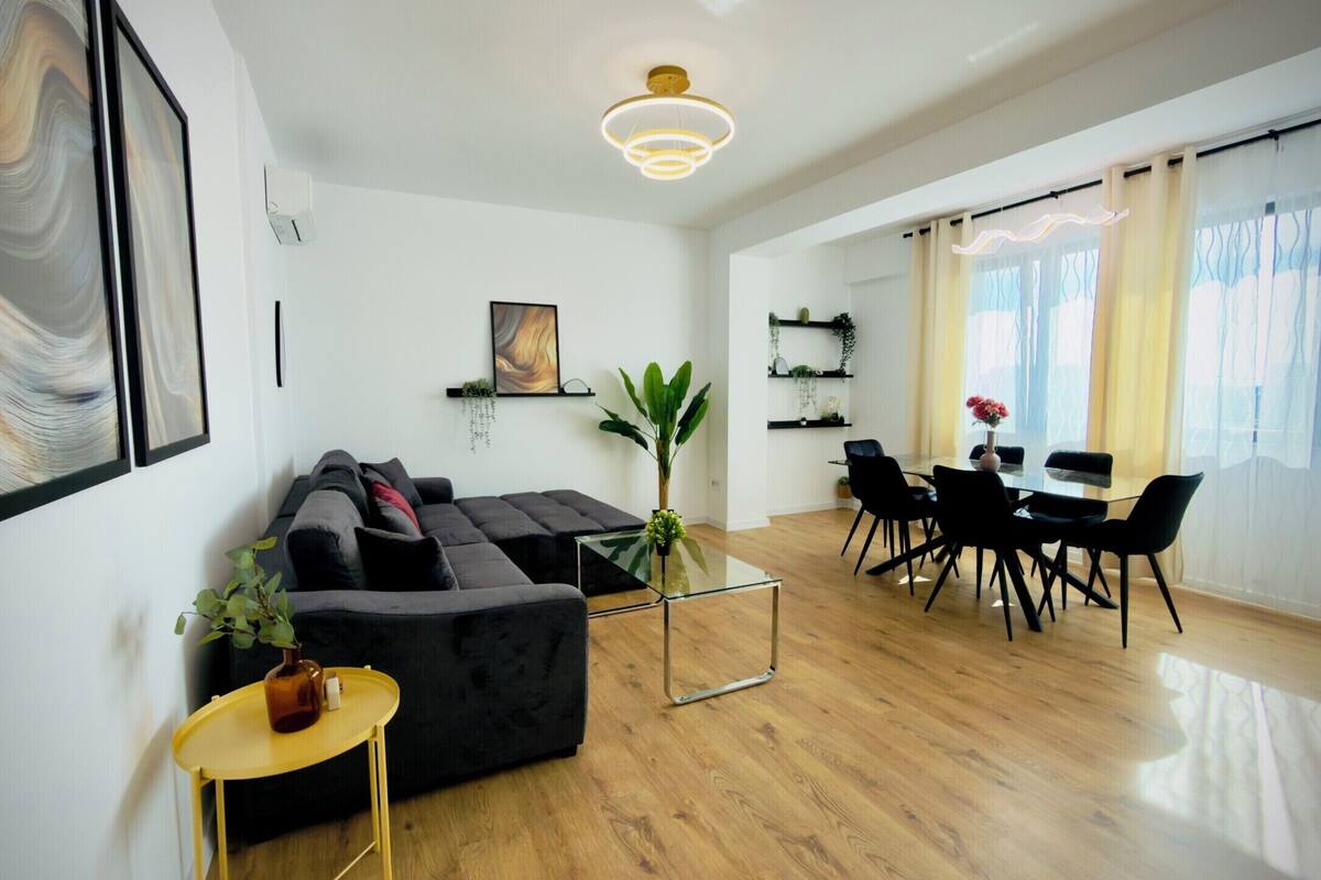 A modern living room with a sectional sofa, a glass coffee table, and a dining area with a table and chairs.