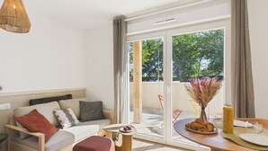 Una sala de estar moderna con un sofá, una mesa de centro y un comedor con una mesa preparada para dos.