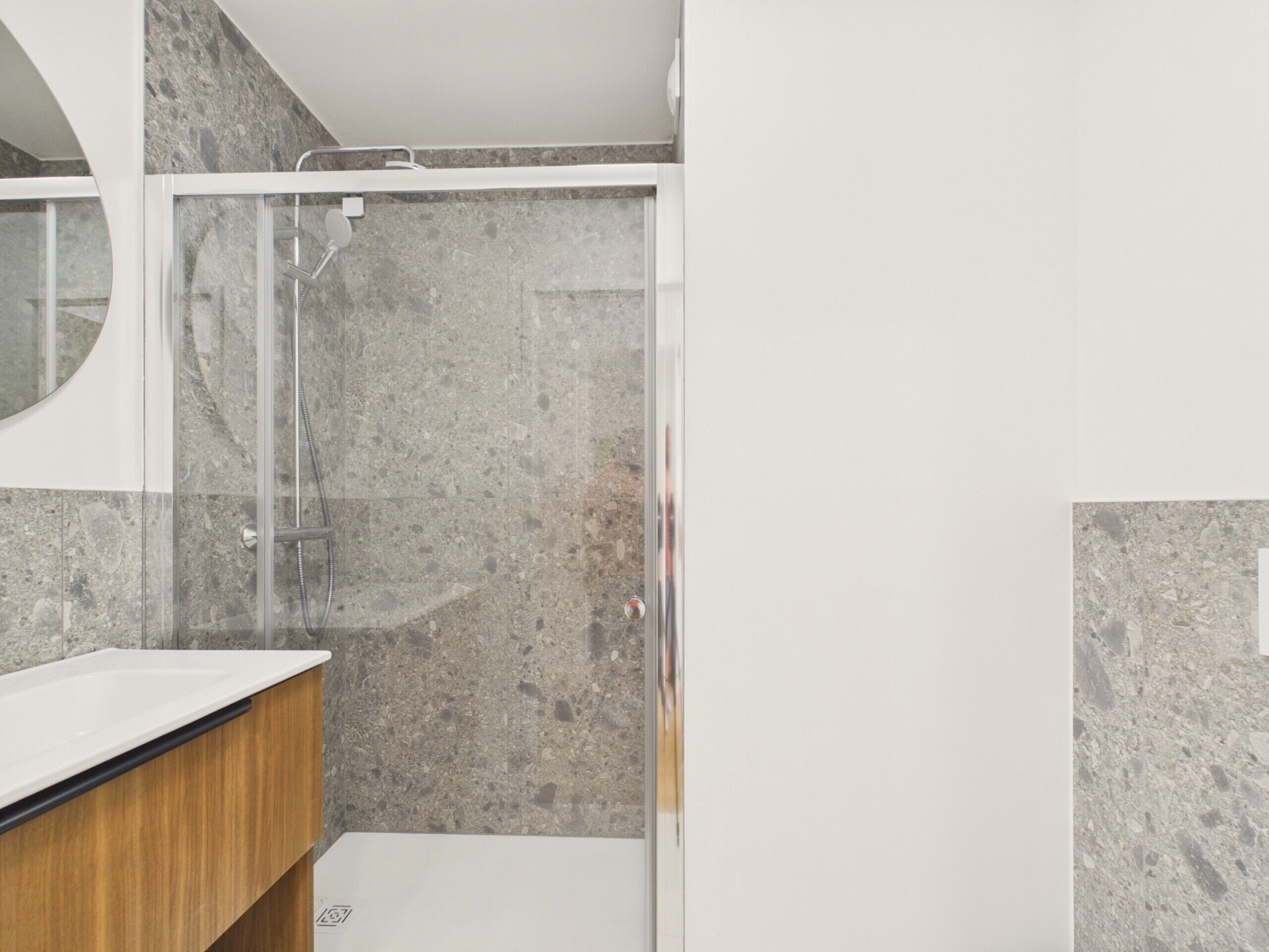 A bathroom with a shower, a sink, and a mirror.