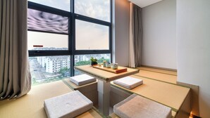 A modern room with a large window, a small table with a plant, and a view of buildings. - Echeng Hotel Wuxi  Airport Branch (Wuxi)