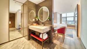 A modern hotel bathroom with a large mirror, a vanity, and a red chair. - Echeng Hotel Wuxi  Airport Branch (Wuxi)