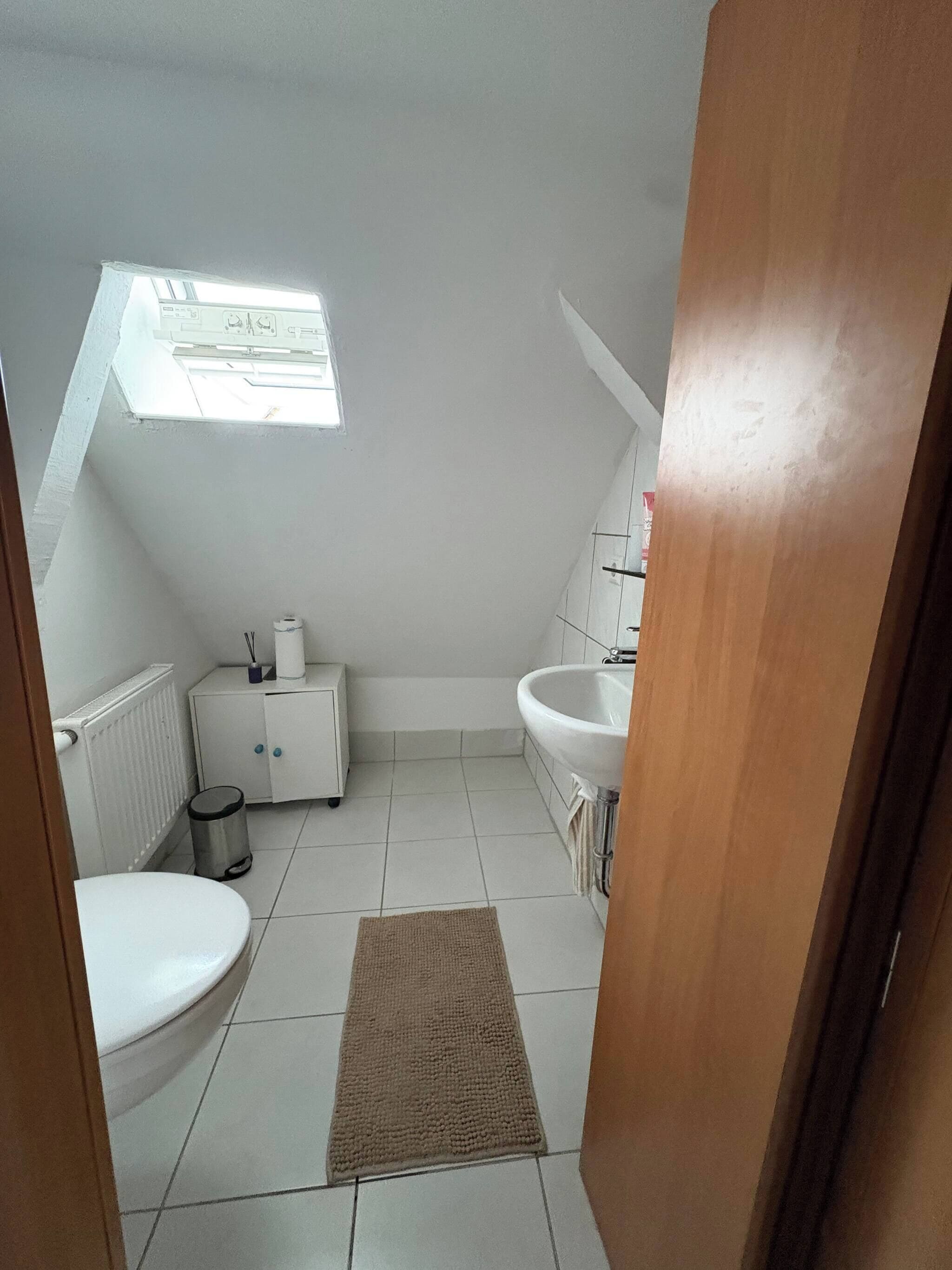 Une petite salle de bain propre, équipée de toilettes, d’un lavabo et d’un meuble de rangement.