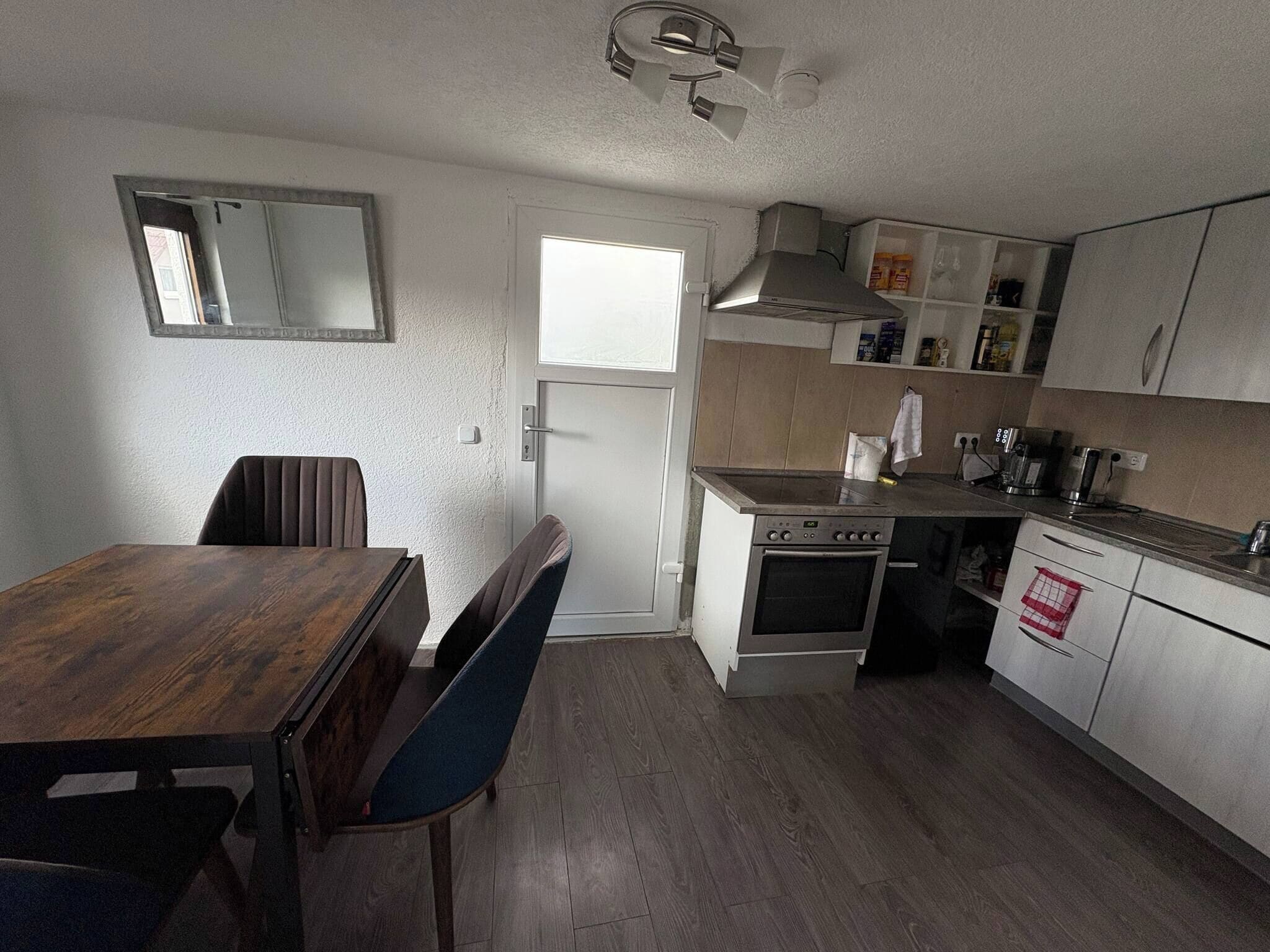 A compact kitchen with a dining table, chairs, a built-in oven, and a microwave.