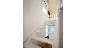 Un escalier avec des rampes blanches et un banc en bois au bas.