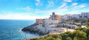 A coastal building complex with multiple structures, including a prominent dome, situated on a rocky shoreline with a view of the sea. - Anemone Studios - Spacious room with extra bed near Otranto (Uggiano La Chiesa)
