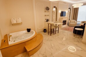 Een luxueuze badkamer met een vrijstaand bad, marmeren vloeren en een zithoek met een tafel en stoelen.